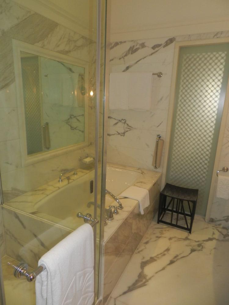Hotel The Taj Mahal Tower, Bombay Esterno foto The photo displays a bathroom featuring a luxurious design. There is a glass-enclosed shower area alongside a large bathtub. The walls are adorned with marble, giving a sophisticated look. A few white towels are neatly arranged, and there is a small 