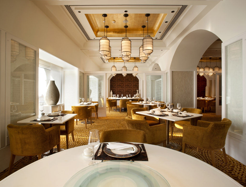 Hotel The Taj Mahal Tower, Bombay Esterno foto The photo shows an elegantly designed restaurant interior. The space features stylish furnishings, including round tables topped with white tablecloths and plush, mustard-colored chairs. The ceiling has a decorative design, with pendant lights hangin