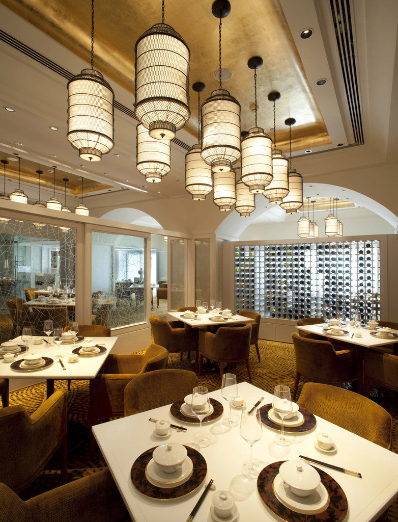 Hotel The Taj Mahal Tower, Bombay Esterno foto The photo depicts an elegant restaurant interior. It features a sophisticated design with multiple hanging light fixtures that have a distinct, stylish appearance. The tables are round and set for dining, with neatly arranged plates and utensils. The