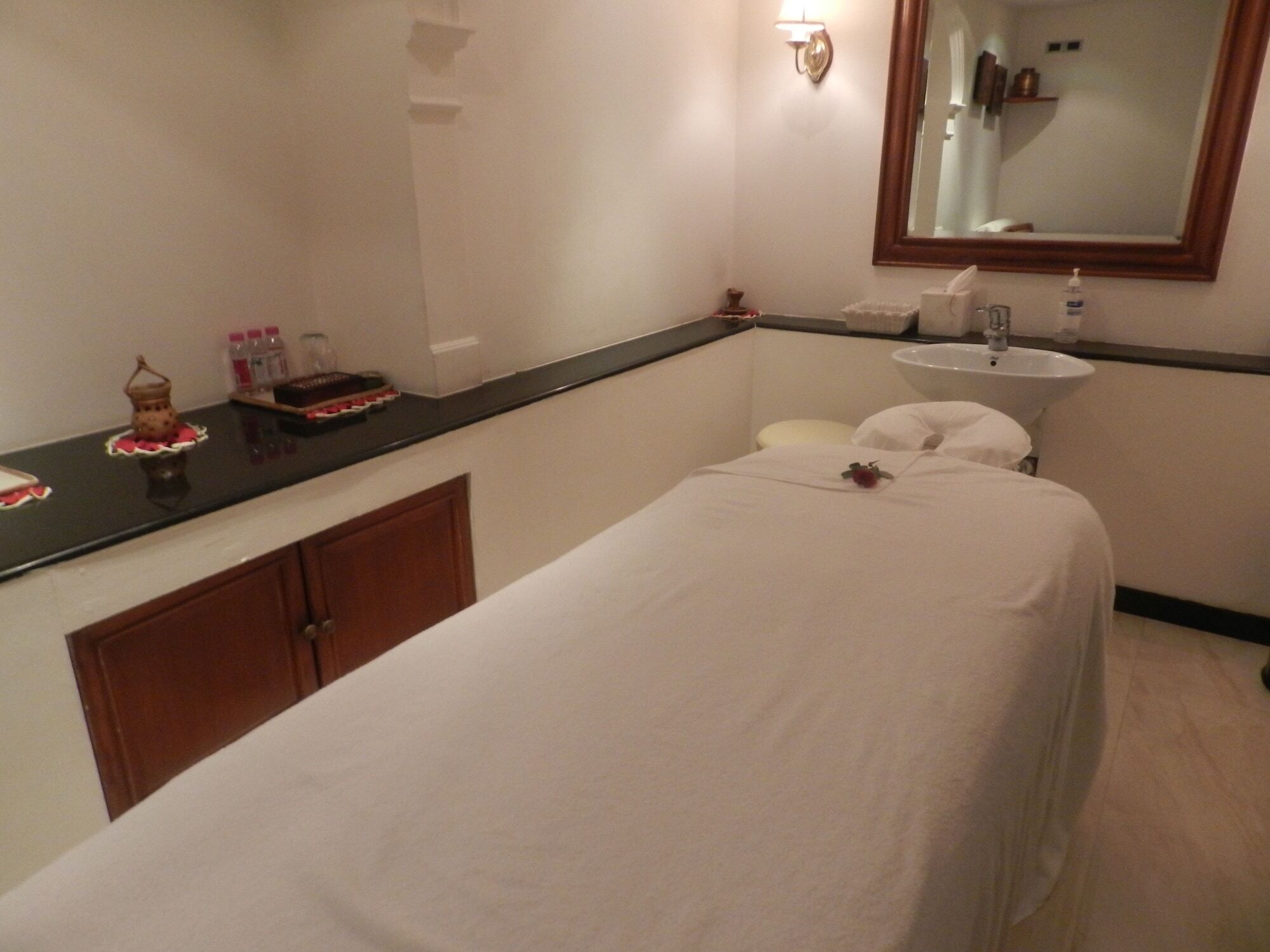 Hotel The Taj Mahal Tower, Bombay Esterno foto The photo shows a serene spa room designed for relaxation and treatments. In the center, there is a massage table covered with a white sheet. There is a small decorative item, possibly a flower, placed on the table. Alongside, a dark countertop displ